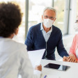 Physician at desk with patient and wife