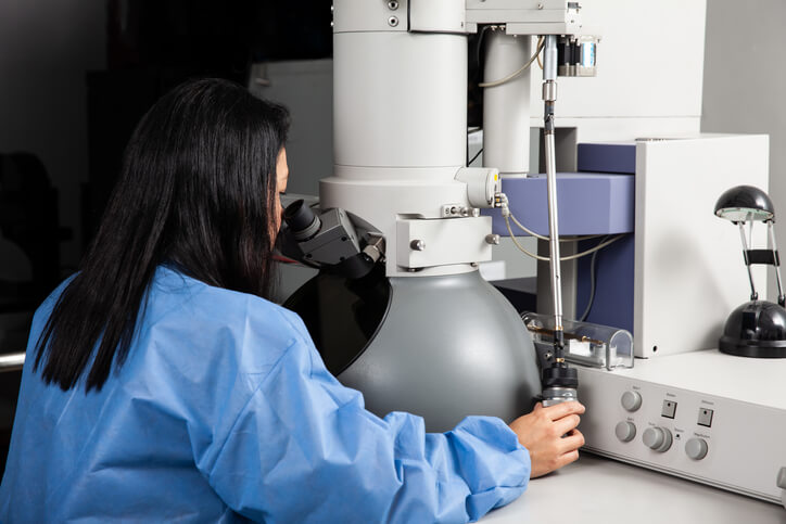 Young female scientist working at the laboratory with an electron microscope.